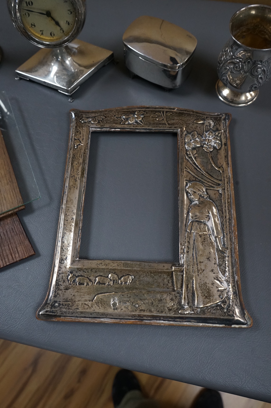 An Edwardian repousse silver mounted photograph frame, decorated with a young lady, flowers and farm animals, Martin, Hall & Co, Birmingham, 1904, 21.7cm, together with a pair of George V silver mounted dwarf candlestick